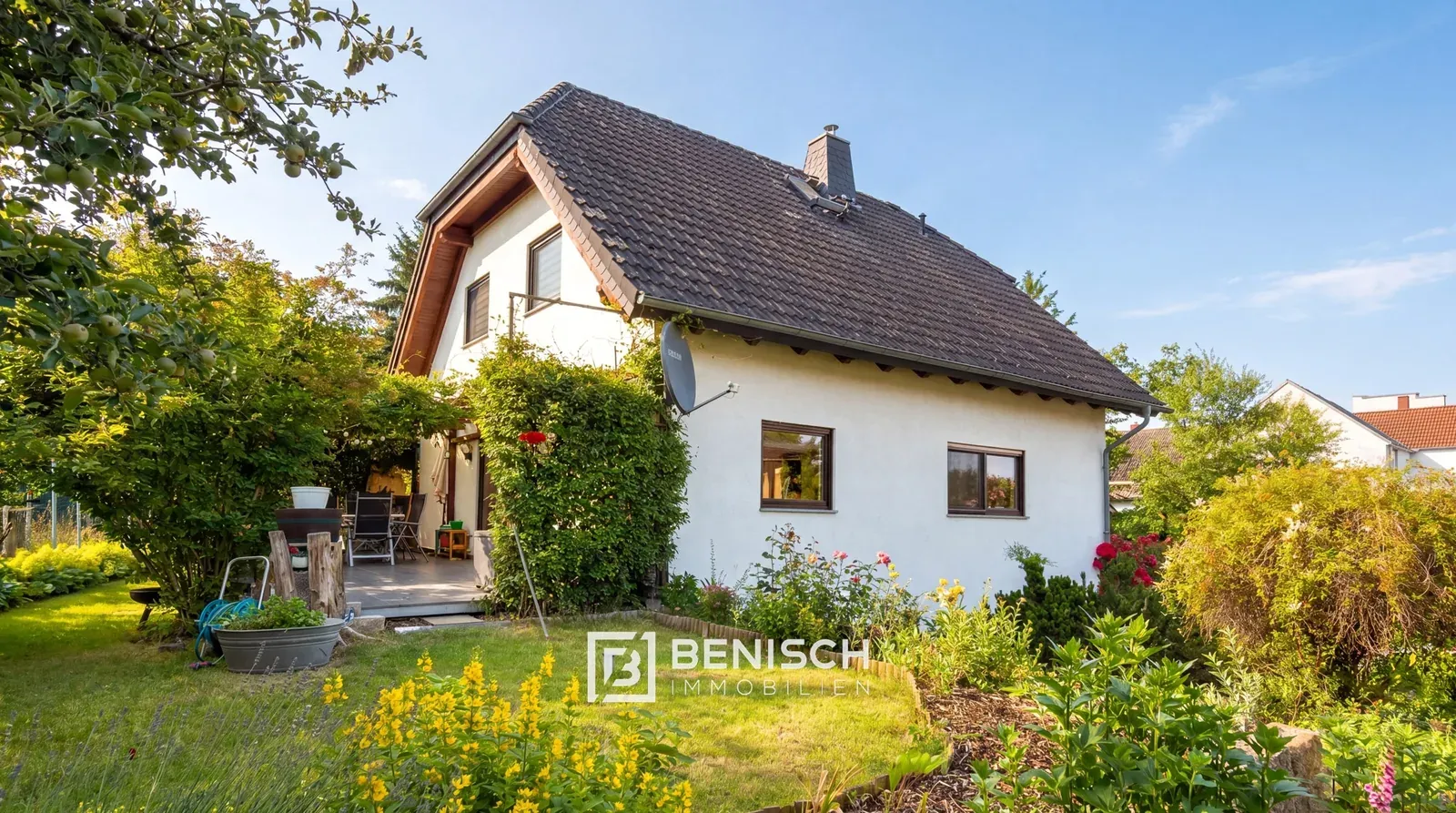 Verkauftes Einfamilienhaus in Moritzburg: Gartenseite mit Terrasse, Rasen und blühenden Beeten