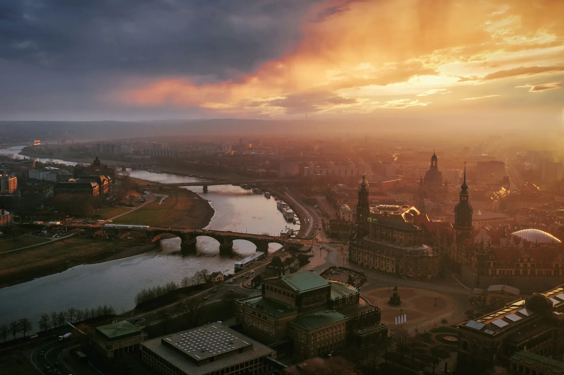 Luftbild von Dresden im Abendlicht: die Elbe mit Augustusbrücke, davor Semperoper, Hofkirche, Residenzschloss und Frauenkirche in der Altstadt