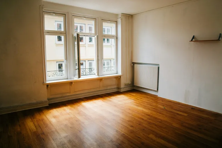 Leeres Zimmer mit Holzdielen und großem Fenster – bereit für die Neuvermietung