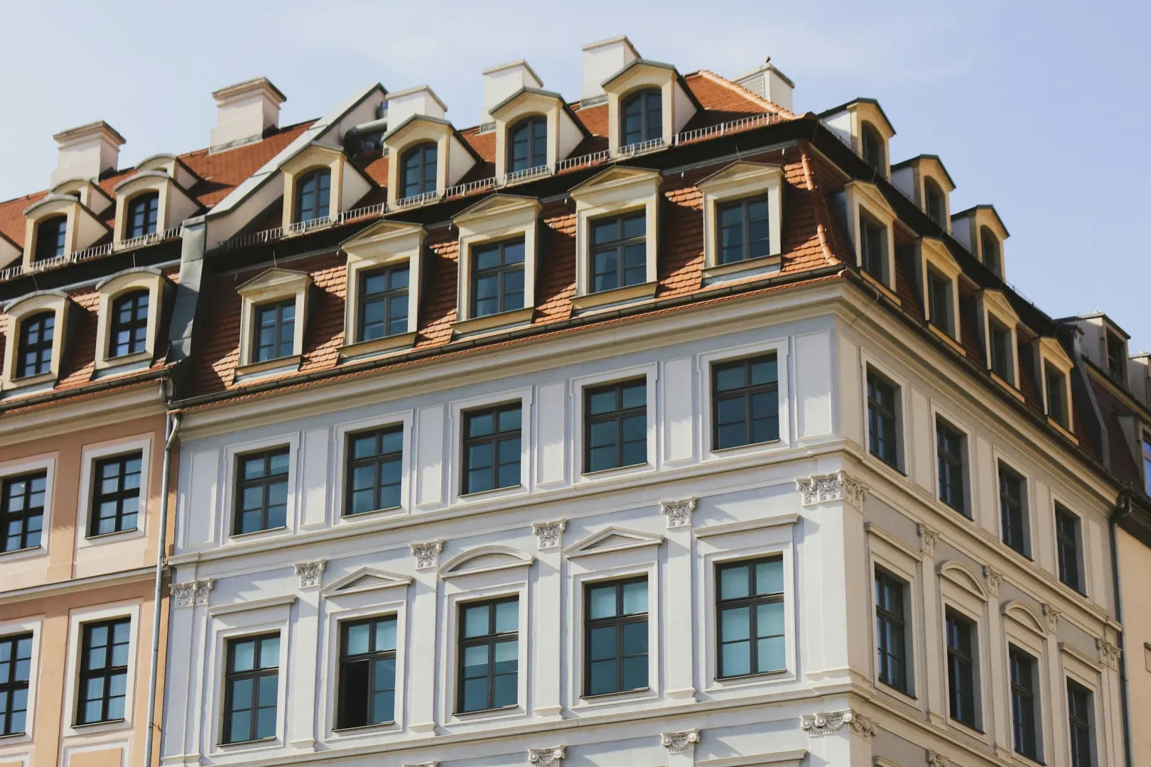 Helle Stadthausfassade mit Stuckrahmen an den Fenstern und Dachgauben in Dresden
